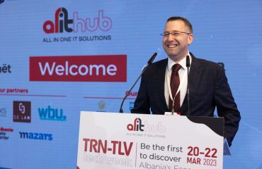 TRN-TLV Tech Week Conference in Albania on March 2023. GNL CEO, Mr. Roi Shaposhnik smiling on the stage with a background and the speaker stand. All the setup was designed by our studio.